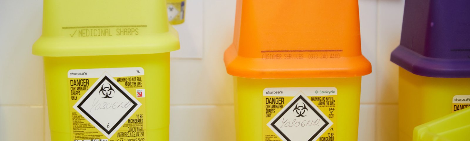 A photo showing three sharps bins
